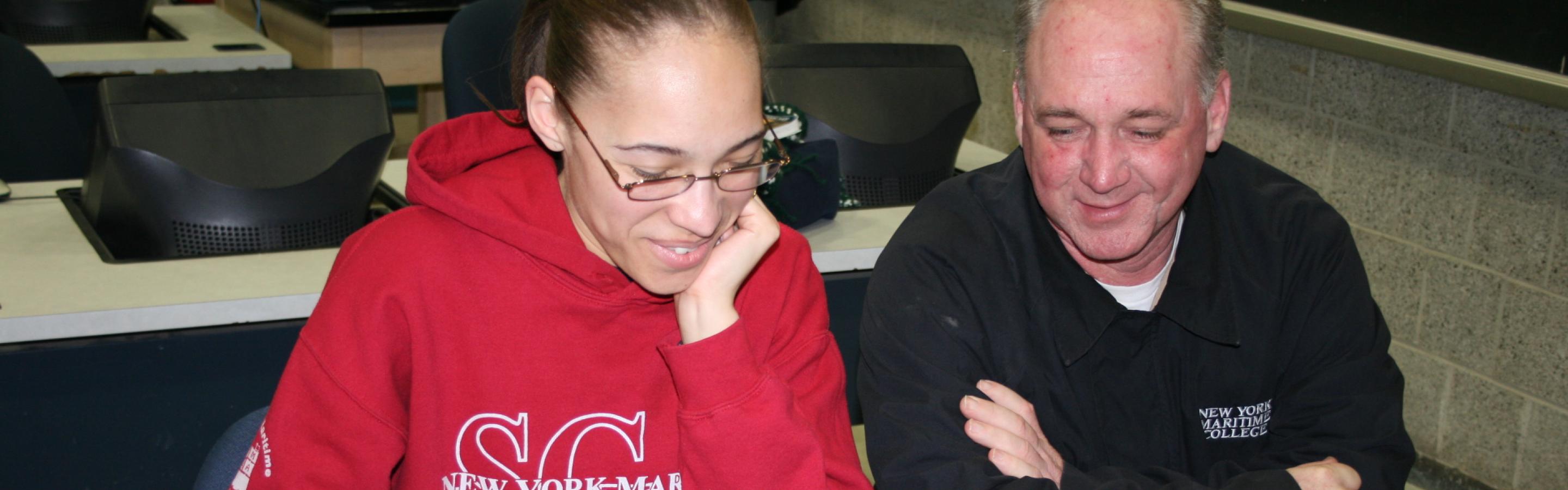Two people sitting at desk looking at computer