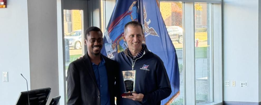 Two men taking a photo with the National Society of Black Engineers award