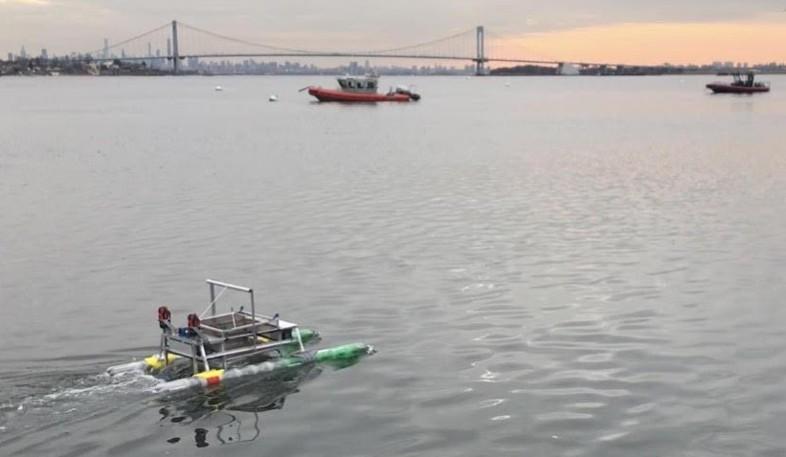 Small, remote-controlled boat moving through the water with the Throggs Neck Bridge in the background