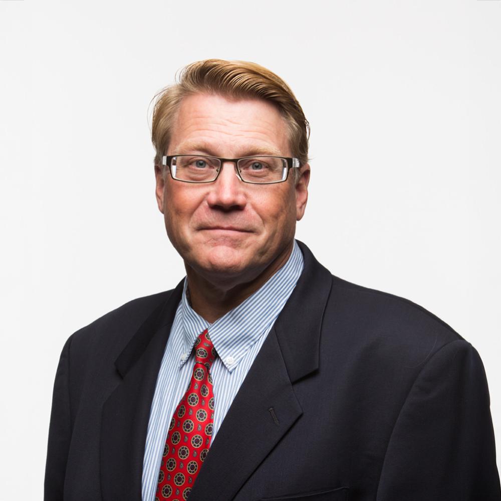 Man with glasses and blond hair looks at the camera